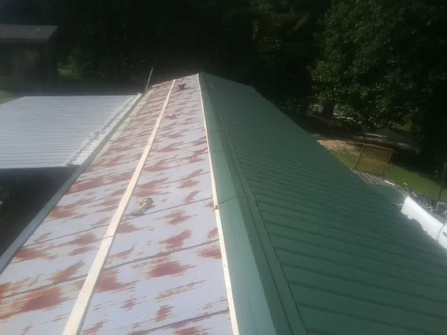 Old rusted panels beside newly installed green metal roofing — Wind Damage Roof Repair by Roofing Brothers in Haddam