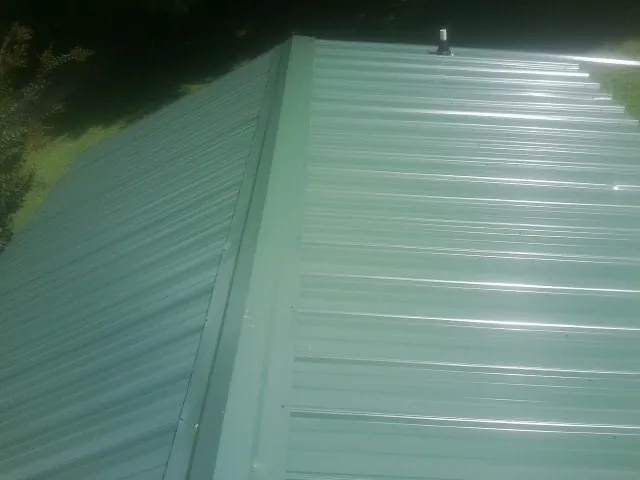 New green metal panels meeting at the ridge of a roof — Flat Roof Repair work by our crew in Haddam