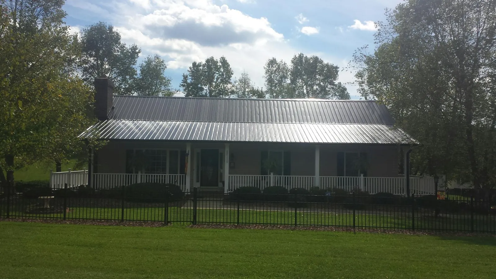 Gray metal roof on a brick ranch with a full width front porch — Gutter Guard Installation work by our crew in Haddam