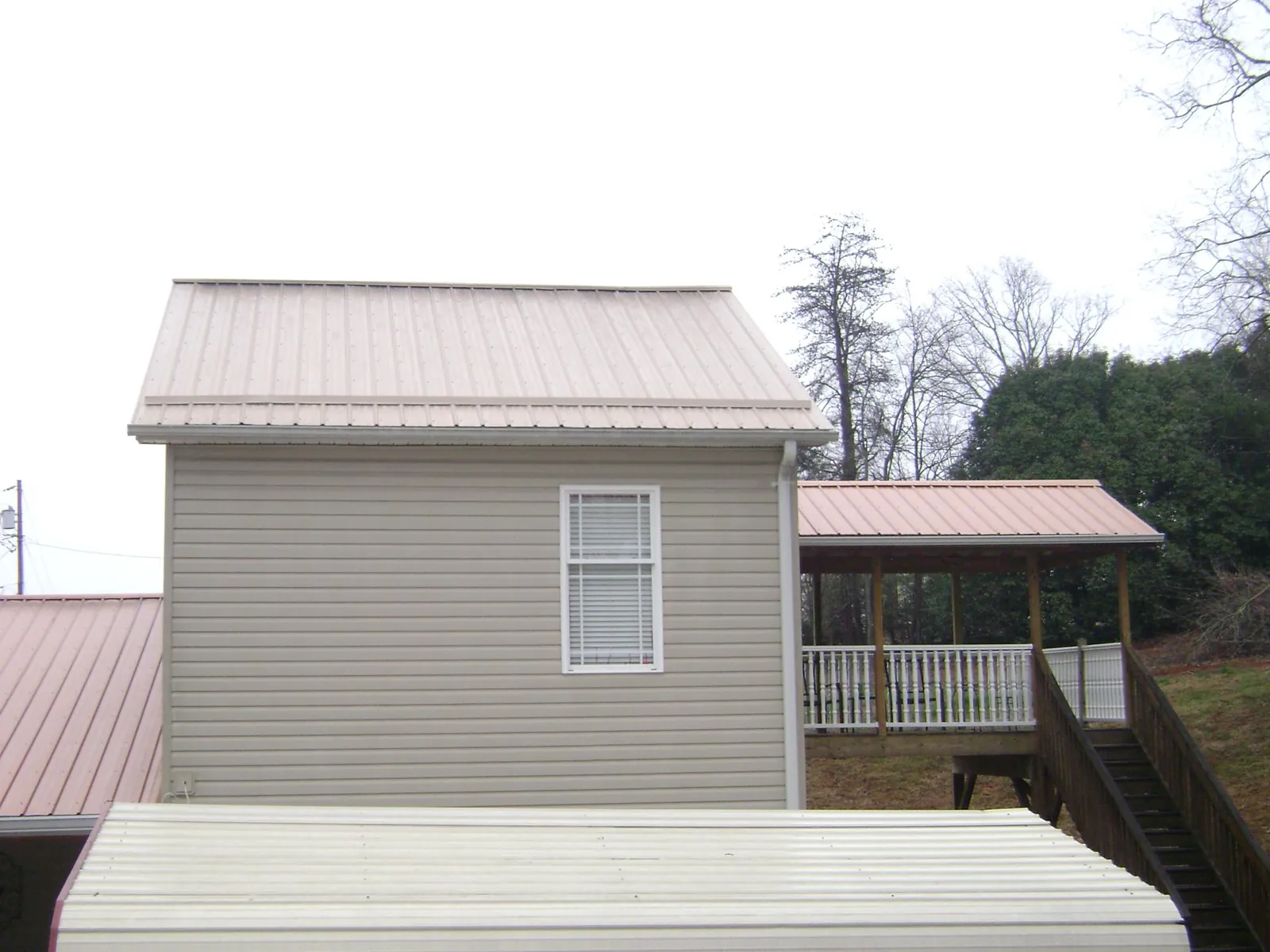 Tan metal roofs on a two story addition and attached porch, from a Roof Replacement job in Haddam