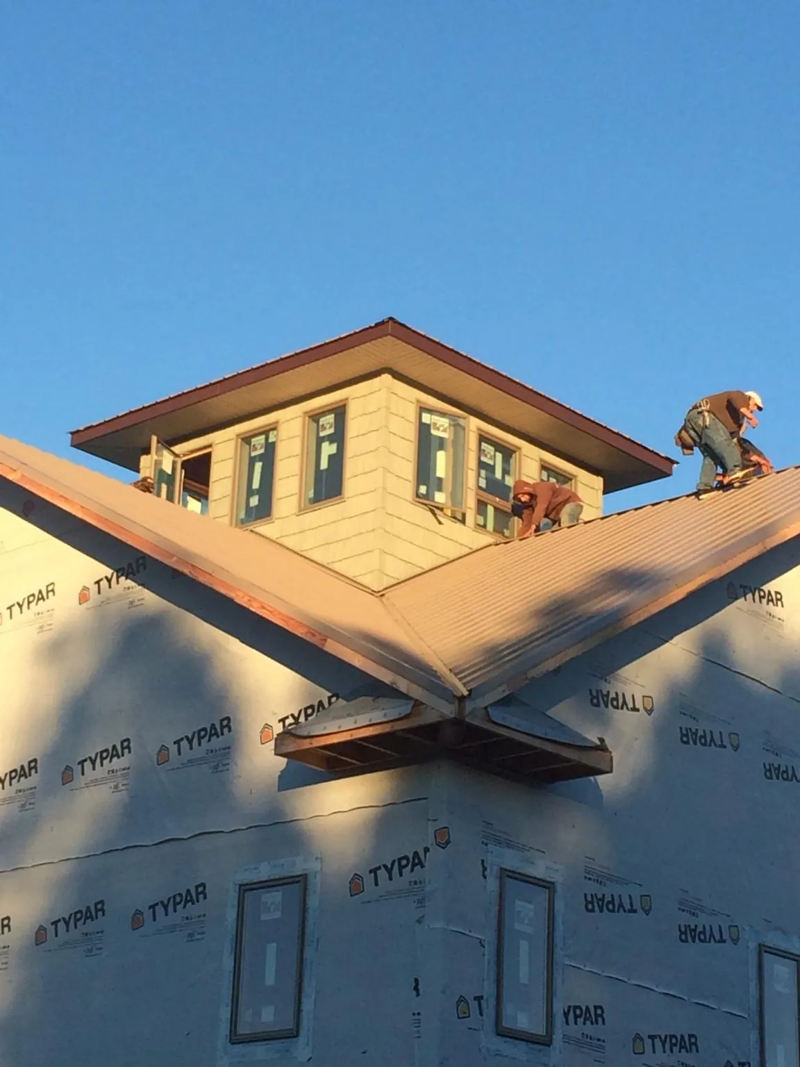 Roofers working around a rooftop cupola on a new metal roof at sunset — Roof Waterproofing in Haddam by Roofing Brothers